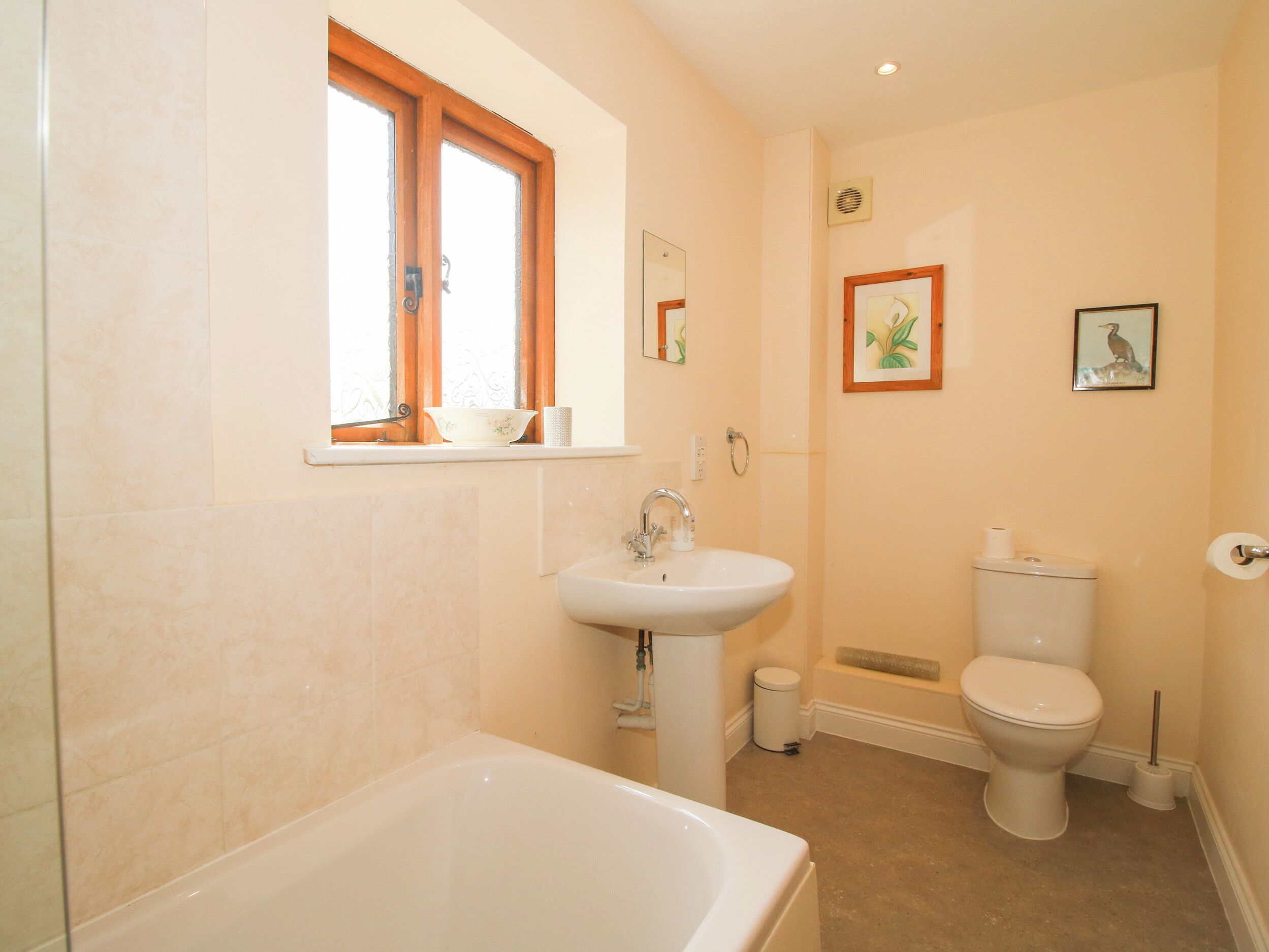 Ein Badezimmer mit Badewanne, Waschbecken, Toilette und einem Fenster mit Vorhängen.