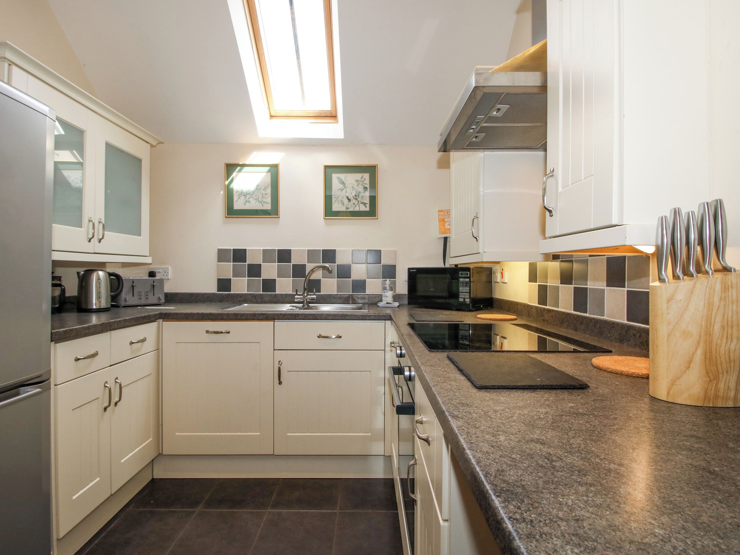A kitchen with white cabinets, a microwave, a kettle, and a toaster.