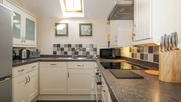 A kitchen with white cabinets, a microwave, a kettle, and a toaster.