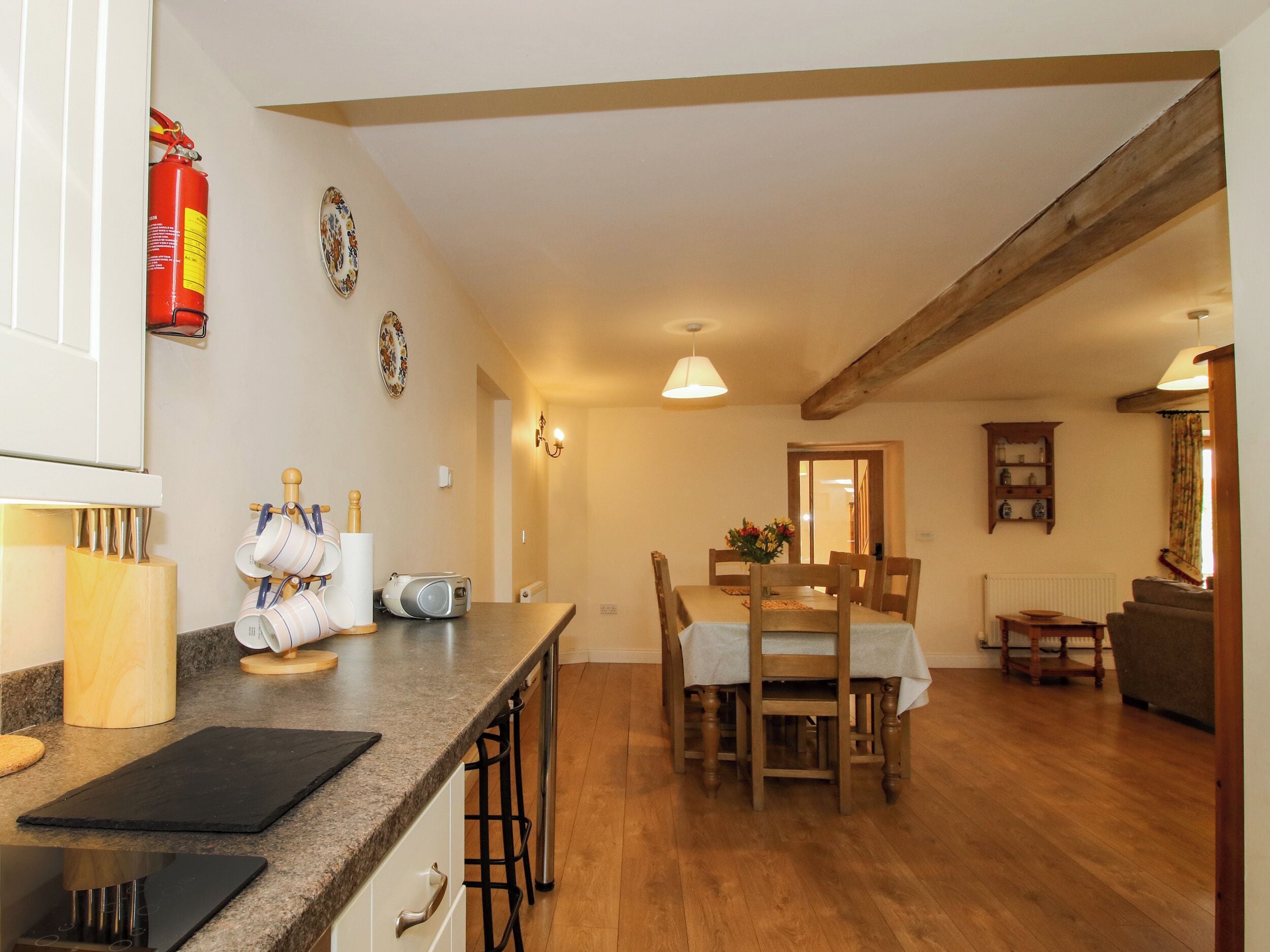 A kitchen with a dining area, wooden beams, and a fire extinguisher.