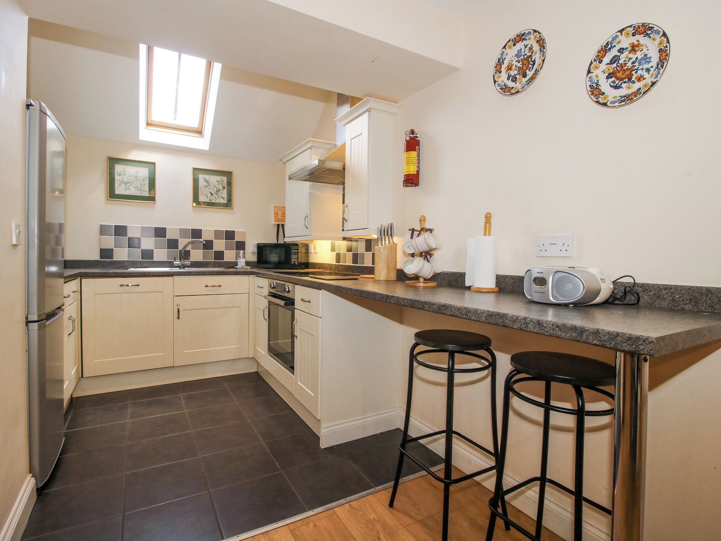 A compact kitchen with a microwave, oven, and a small bar area with stools.