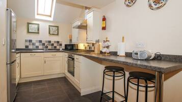 A compact kitchen with a microwave, oven, and a small bar area with stools.