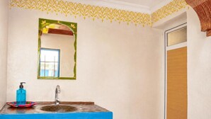 Ein Badezimmer mit blauem Waschbecken, einem Spiegel und einem dekorativen Wandmuster.