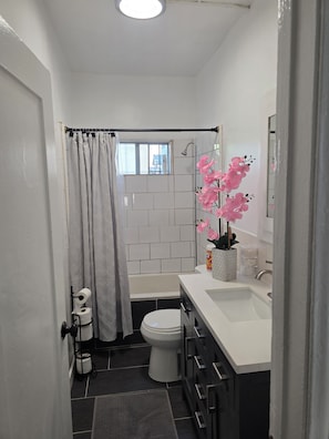 A compact bathroom with a shower, toilet, and sink. - Cozy 1-Bedroom Urban Retreat with Modern Comforts (Los Angeles)