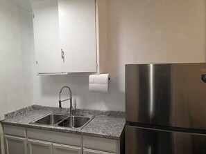 A kitchen with a stainless steel refrigerator, a double sink, and a white cabinet above the sink. - Cozy 1-Bedroom Urban Retreat with Modern Comforts (Los Angeles)