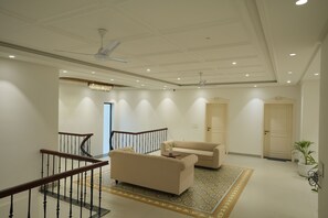 A spacious living area with a staircase, two sofas, a patterned rug, and a ceiling fan.