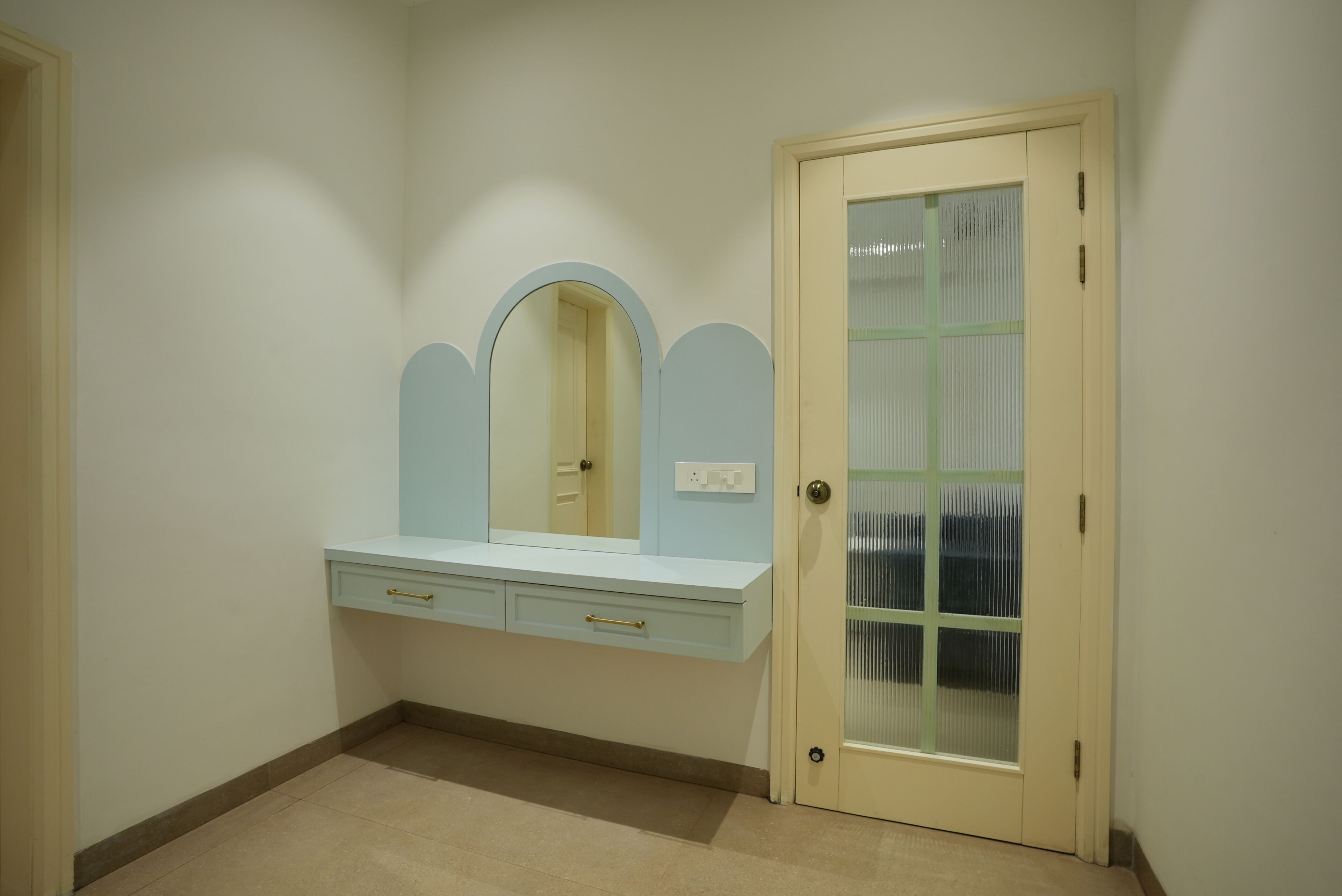 A room with a vanity, a door with a frosted glass panel, and a light switch on the wall.