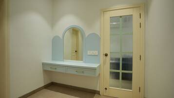 A room with a vanity, a door with a frosted glass panel, and a light switch on the wall.