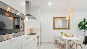 Et moderne køkken med en Hisense mikrobølgeovn, et rustfrit stål emfang og et spiseområde med et hvidt bord og stole.