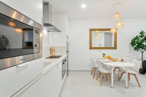 Eine moderne Küche mit einer Hisense-Mikrowelle, einer Edelstahl-Dunstabzugshaube und einem Essbereich mit einem weißen Tisch und Stühlen.