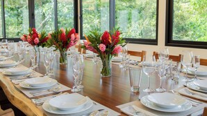 Ein Esstisch, festlich gedeckt für ein formelles Essen, mit mehreren Platzdeckern, Gläsern und Blumenvasen.