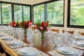 A dining table set for a formal meal with multiple place settings, glasses, and vases of flowers. - Luxury Brand New : Casa Rambutan - 3BR (Quepos)