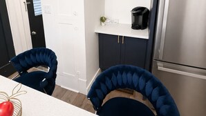 Una cocina moderna con refrigerador empotrado, una cafetera negra y una pequeña planta en maceta sobre la encimera.