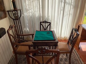Ein Essbereich mit Tisch, Stühlen, einer Lampe und Blick durch transparente Vorhänge.