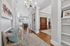 A spacious hallway with a wooden bench, a chandelier, and a large wooden cabinet. - Sandy Cove Cottage- Great Waters Lakefront Luxury (Eatonton)