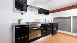 Una cocina moderna con estufa a gas, horno, microondas y lavadora integrada.