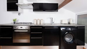 Una cocina moderna con armarios negros, horno empotrado, lavadora y estufa.