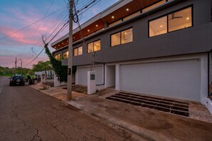 A modern two-story house with a garage, a driveway, and a parked car. - TW9 4BR Retreat w Saltwater Pool Walk to Beach & Town (Tamarindo)