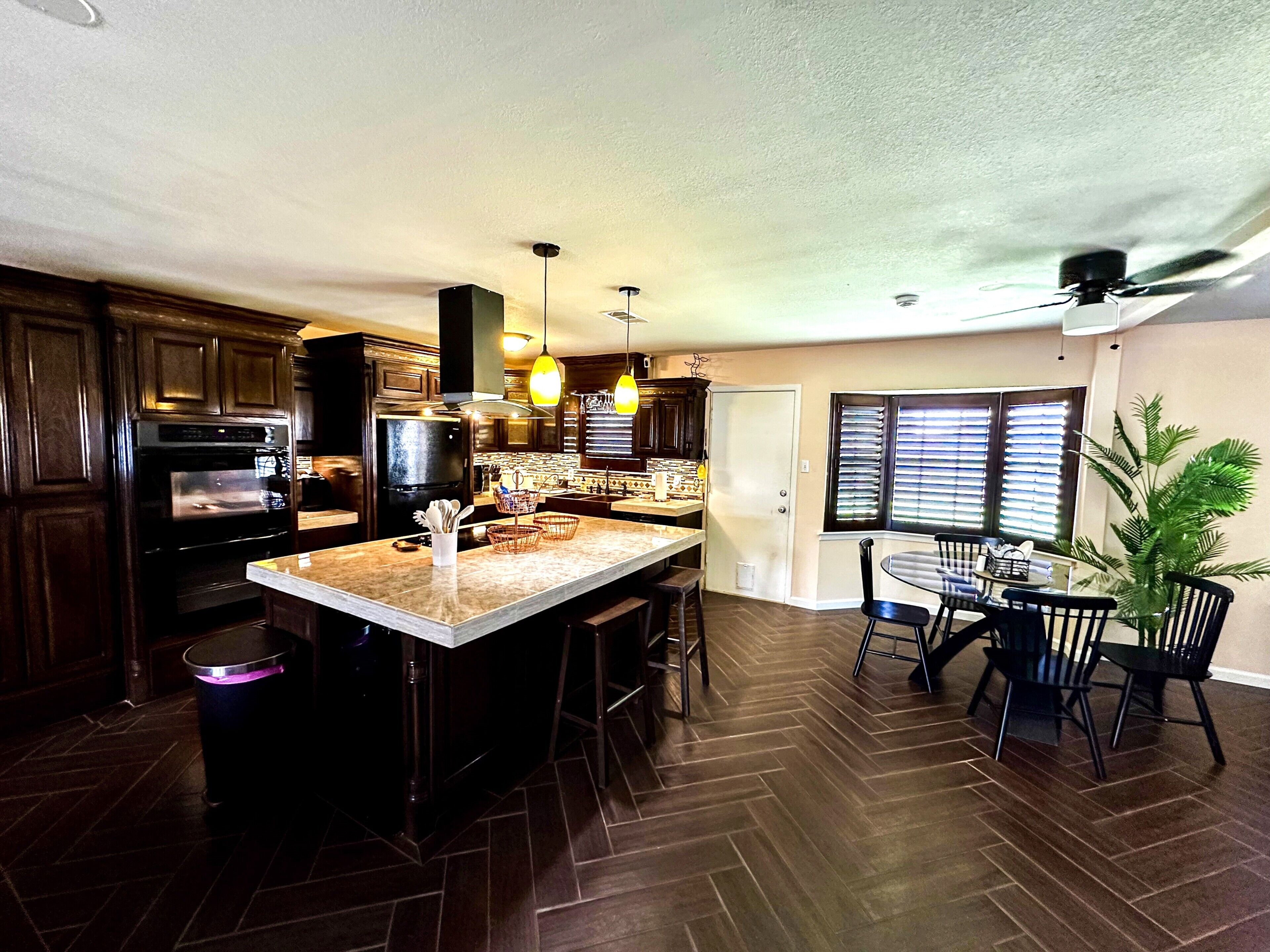 A kitchen with dark wood cabinets, a central island, and a dining area with a table and chairs.