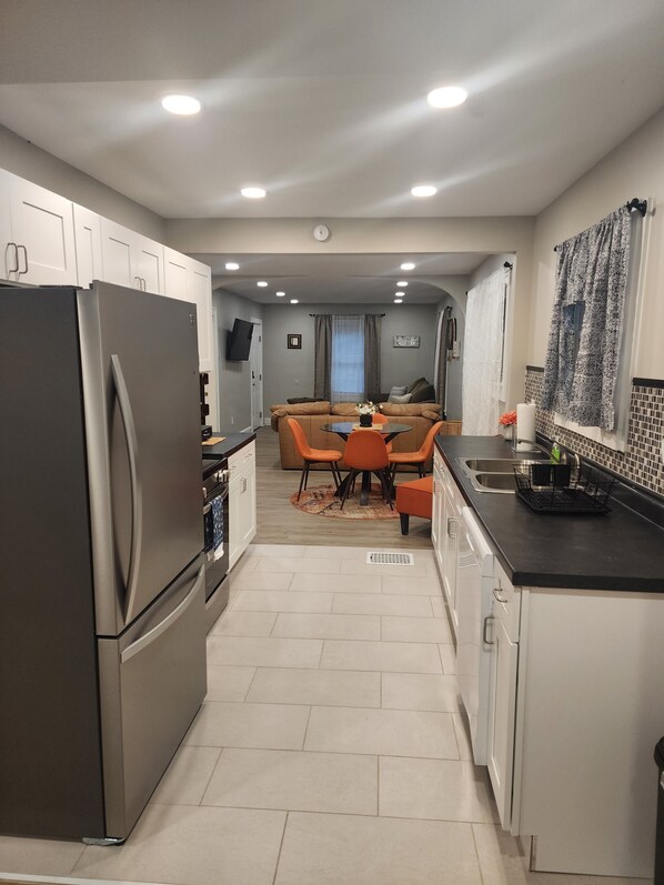 A modern kitchen with a refrigerator, dining table, and chairs.