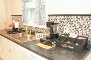 A kitchen with a coffee bar, a coffee maker, and a sign that says 'Coffee Bar'.