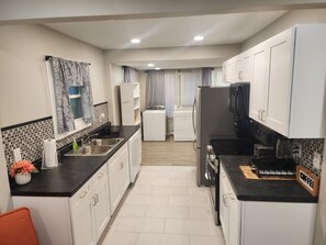 A modern kitchen with white cabinets, black countertops, a built-in oven, and a microwave.