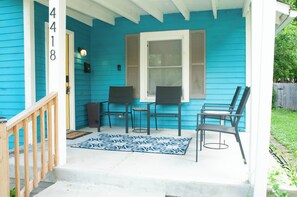 A porch with a blue exterior, a number '418' on the wall, and two chairs with a small table.