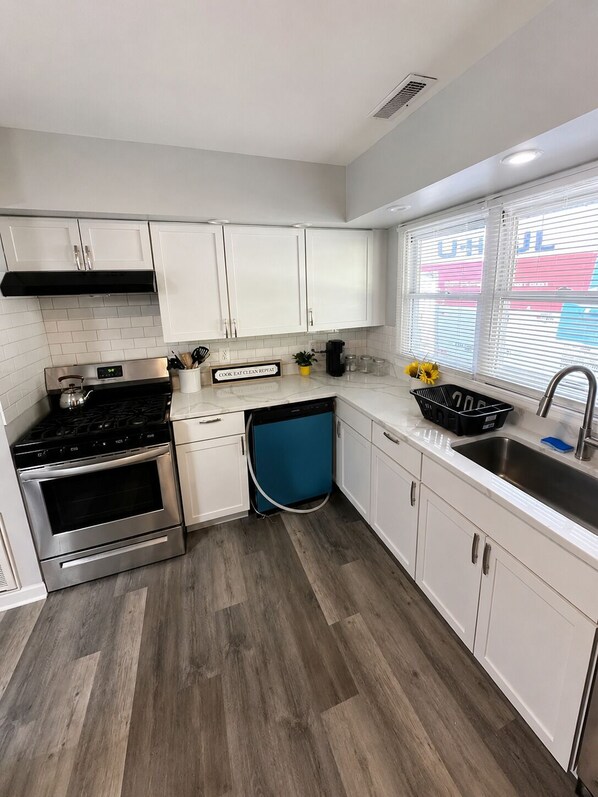 A modern kitchen with white cabinets, a stainless steel stove, and a dishwasher.
