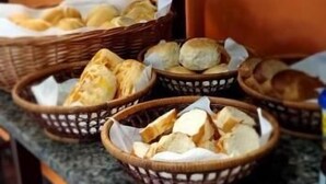 Una mesa de buffet con cestas de pan y pasteles, un juego de cuchillos y frascos de condimentos.