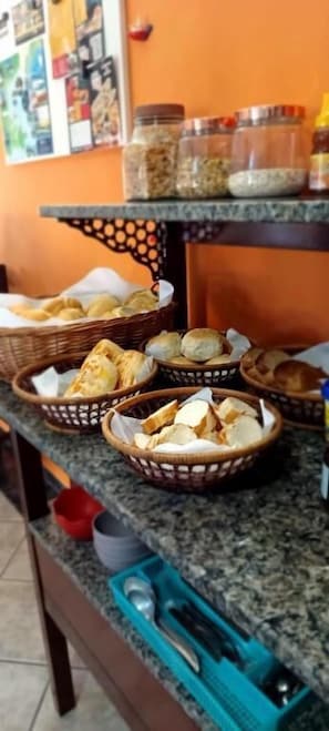 Una mesa de buffet con cestas de pan y pasteles, un juego de cuchillos y frascos de condimentos.