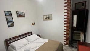 Un dormitorio con cama, ventilador de techo, televisor y pared de ladrillo.