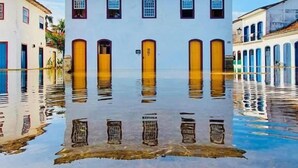 Un edificio con fachada blanca y puertas amarillas, rodeado de agua.