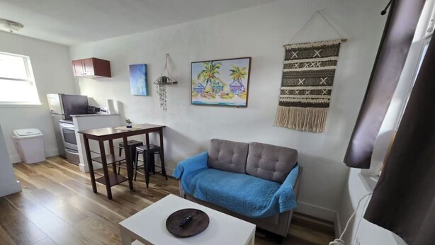 Un salon comprenant un canapé, une table basse, une table à manger et un coin cuisine.