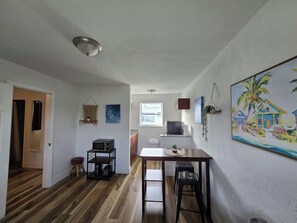 Eine kleine Küche mit Mikrowelle, Esstisch und Fenster.
