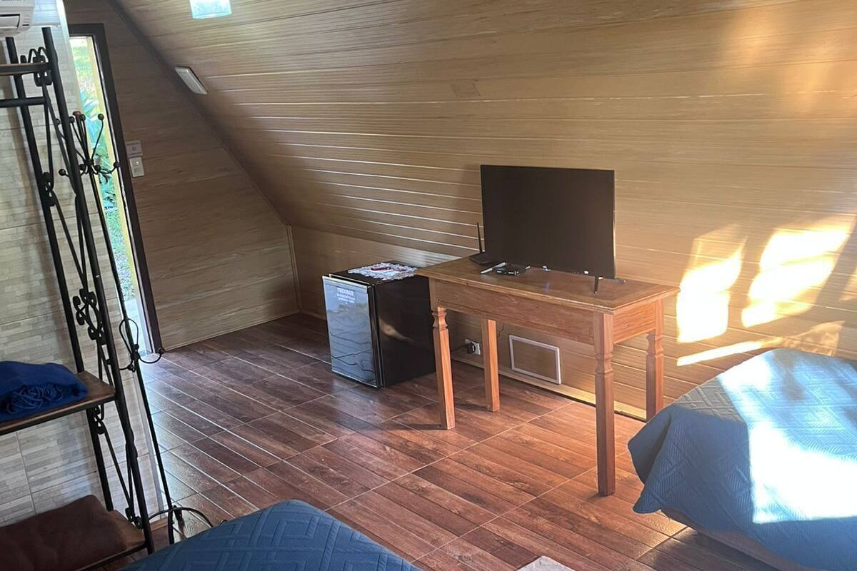 Una habitación con cama, un escritorio con computadora y un refrigerador pequeño.