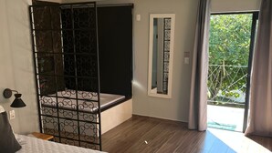 A bedroom with a bed, a large window, and a balcony.