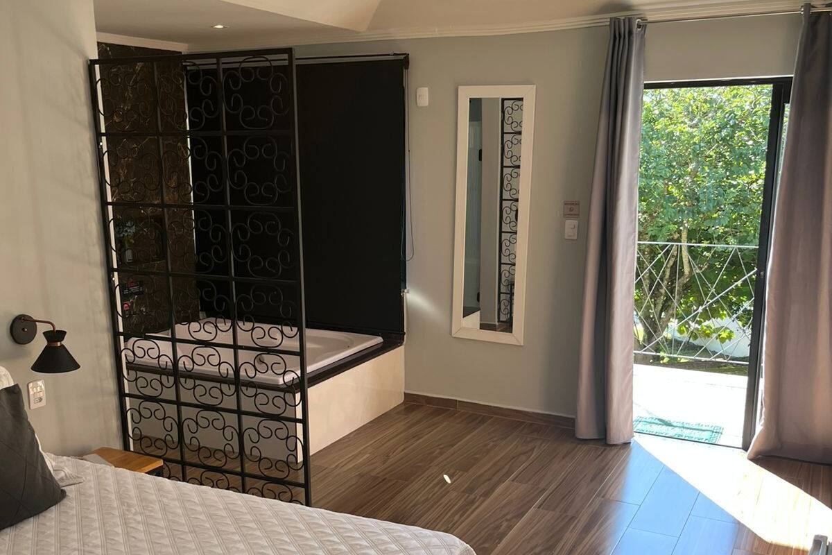 Un dormitorio con una cama, un ventanal grande y un balcón.