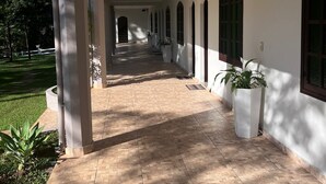 A covered corridor with tiled flooring, white walls, and arched windows.