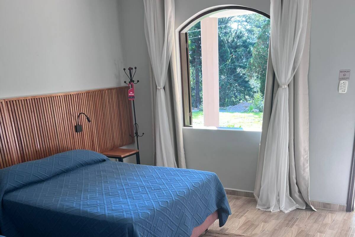 Un dormitorio con dos camas, cabeceros de madera, una ventana con cortinas y una alfombra marrón.