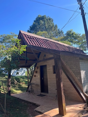 A small building with a sloped roof, a door, and a small outdoor seating area.