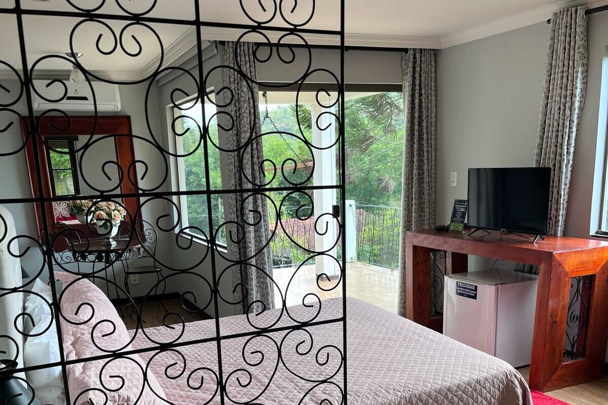 Un dormitorio con cama, escritorio, televisión y vistas al exterior.