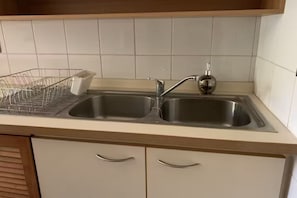 Une cuisine équipée de deux éviers en acier inoxydable, d’un égouttoir et d’un plan de travail en bois.