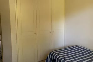 Une pièce avec un lit, une armoire et un mur uni.