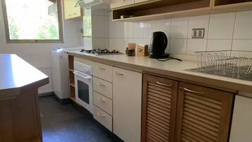 Een keuken met een fornuis, oven en kastjes.
