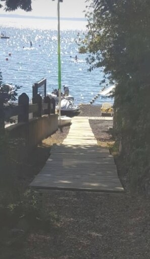 Ein Weg, der zu einem Strand mit einer Holzterrasse und einem Metallgeländer führt.