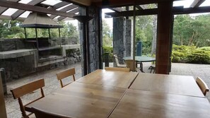 Un'area pranzo all'aperto coperta con camino in pietra, sedie di legno e un tavolo.