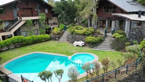 Ein Wohngebäude mit Schwimmbecken, Steinstufen und einem gepflegten Garten.