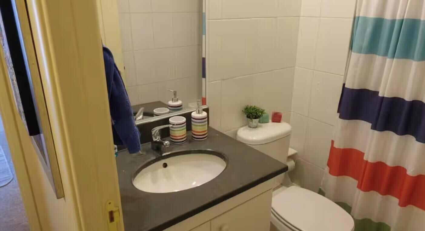 A bathroom with a sink, toilet, and a shower curtain.