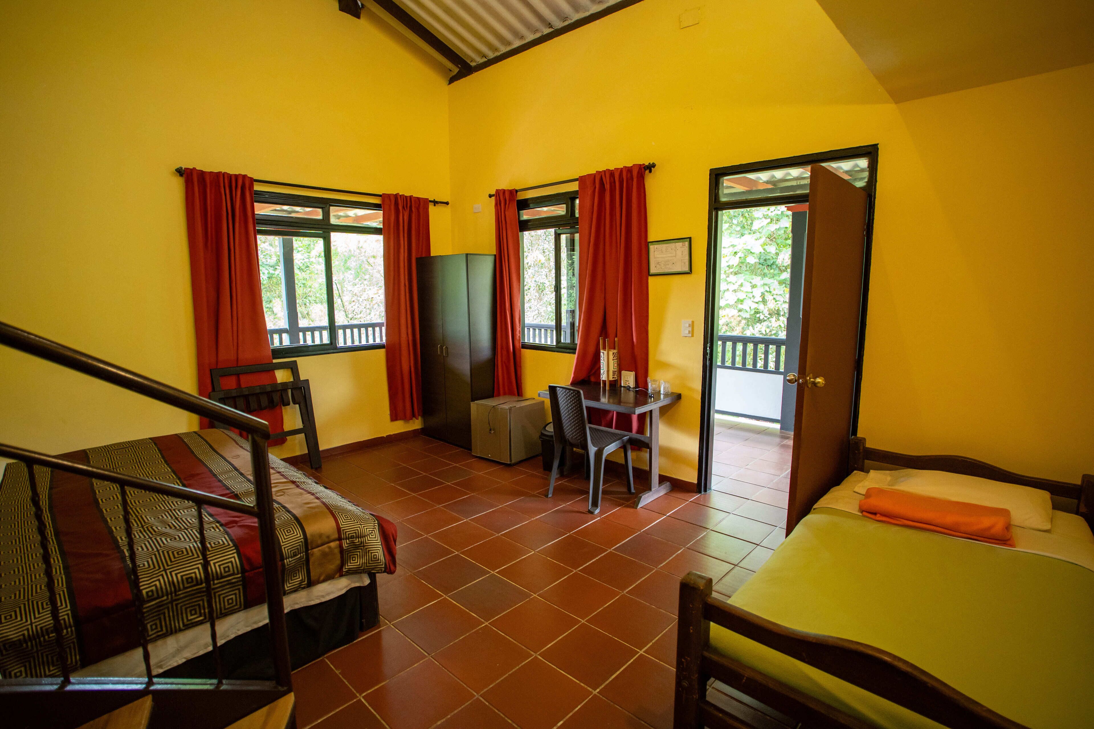 A room with a bed, a desk, a chair, a wardrobe, and a door leading outside.