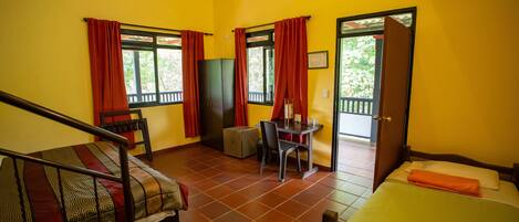 Una habitación con cama, escritorio, silla, armario y puerta que da al exterior.